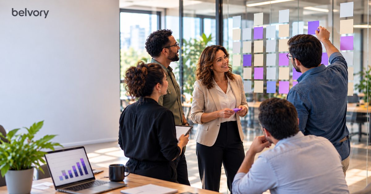 Equipe organiza notas em um quadro de vidro enquanto colegas acompanham em uma sala de reunião